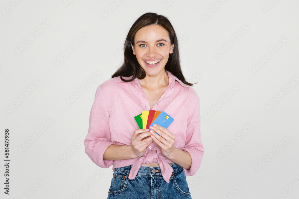 Cool european lady showing bank cards, grey background Cool european lady showing bank cards, grey background