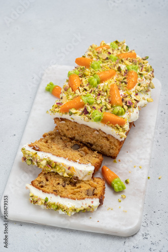 carrot loaf cake with walnuts decotated with cream cheese, candy carrot and pistachios photo