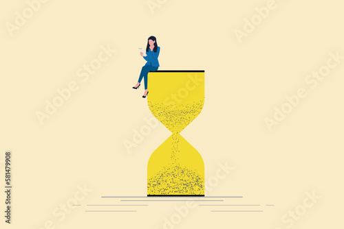 Business woman using laptop sitting on an hourglass. Concept of multitasking, productivity and time management