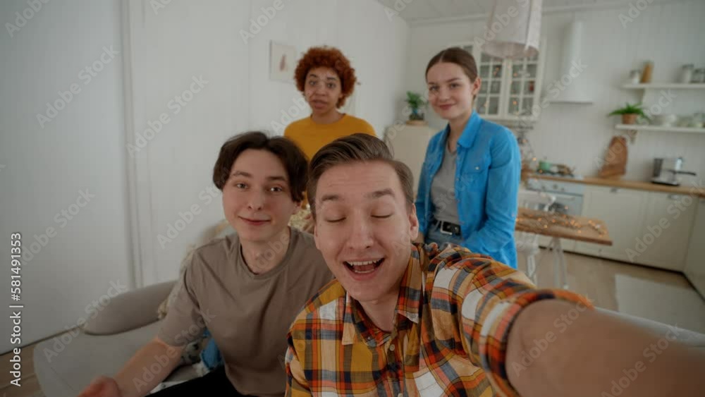 Selfie video of emotionally singing group of young friends girls and guys looks at camera in living room at home. They smile and talk looks at camera. Happy company, friendship, video call concept. Selfie video of emotionally singing group of young friends girls and guys looks at camera in living room at home. They smile and talk looks at camera. Happy company, friendship, video call concept.