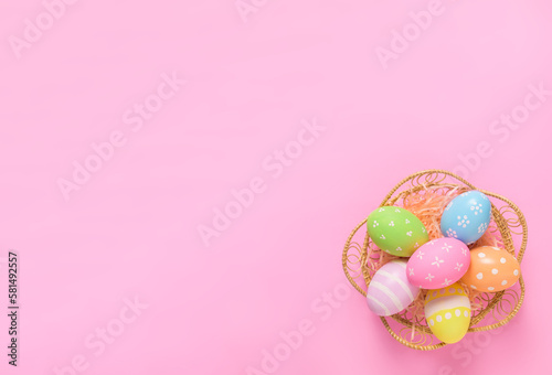 Happy Easter holiday greeting card concept. Colorful Easter Eggs on pastel pink background. Flat lay, top view, copy space.