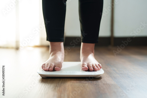 Woman feet standing on digital scales for diet control..