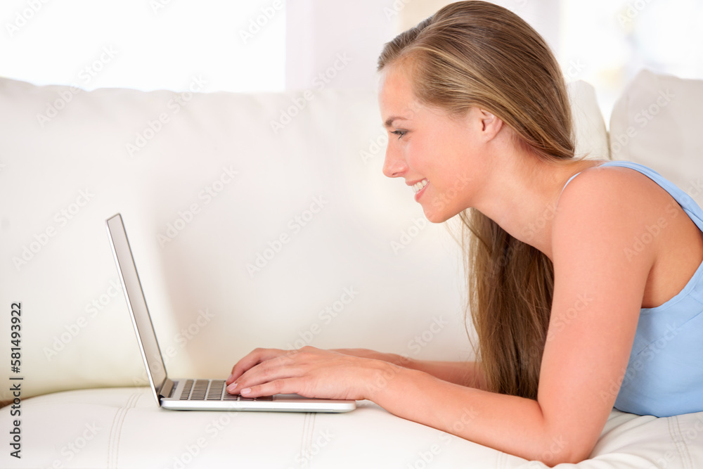 Chatting with friends online. an attractive young woman using a laptop while lying on the sofa. Chatting with friends online. an attractive young woman using a laptop while lying on the sofa.
