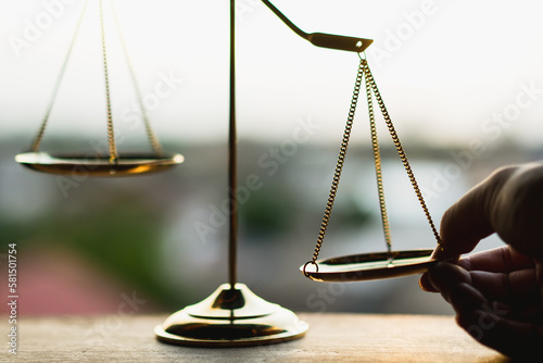Tip the scales of justice concept as a the hand of a person illegally influencing the legal system for an unfair advantage.	 photo