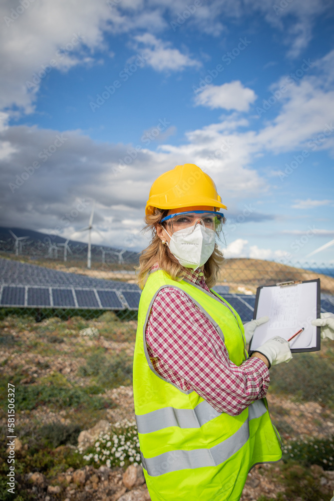 A female engineer at a solar power plant during work, she wears protective workwear