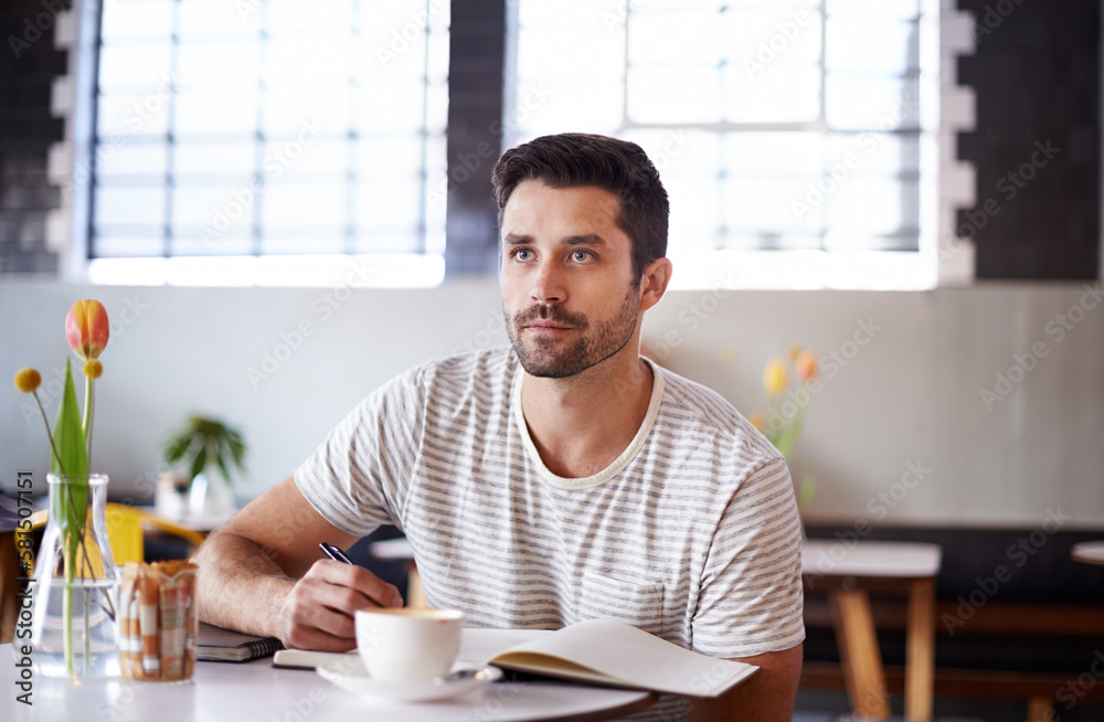 The write stuff. a handsome young man writing in a notebook while sitting at a restaurant table. The write stuff. a handsome young man writing in a notebook while sitting at a restaurant table.