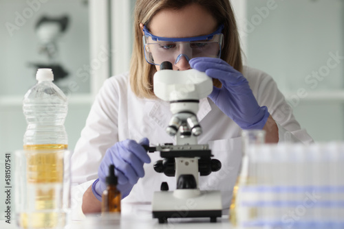 Female scientist in glasses looking at test samples through microscope.