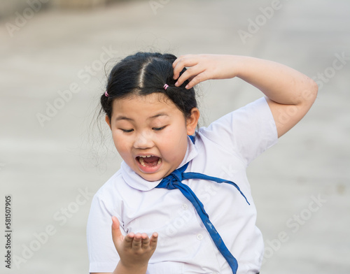 Child student fierce, mad, maniac, maniacal, rabid, wild because lice on the head,she is symptoms itching,scratch head for lice and frightened,agape