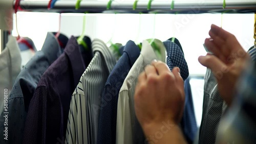 man picks out his outfit from rack of clothes	 photo