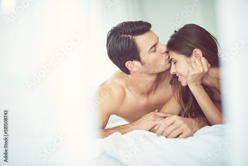 Romantic, love and man kissing his wife in the morning after an anniversary, date or intimate time in bed. Gratitude, relax and young couple in the bedroom showing care and bonding for valentines day