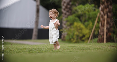 Funny little baby running in the garden on a hot summer day. Cute caucasian baby running on grass in park. Little adorable child happily smiling, expressing emotions - happy childhood concept  © andreybiling