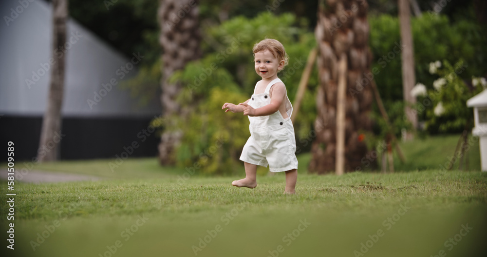 Copy Space. Cute little boy runs around in a city park. Baby toddler have a fun running in garden on the grass . Little baby walking alone. Warm summer day. Baby is very fun.Happy childhood concept Copy Space. Cute little boy runs around in a city park. Baby toddler have a fun running in garden on the grass . Little baby walking alone. Warm summer day. Baby is very fun.Happy childhood concept