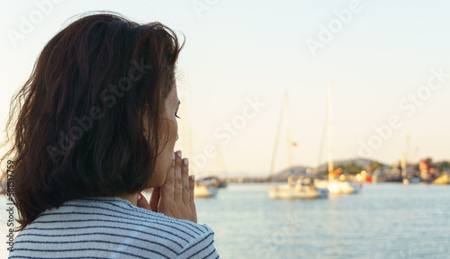 Young woman praying on beach. Blank copy space on sky and blue sea for advertising texts. © Akin Ozcan