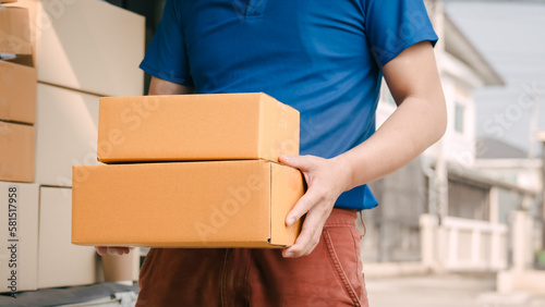 Close up logistic worker delivering cardboard boxes to recipient at home door. © Ratirath