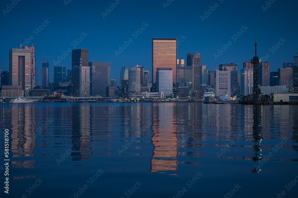 Obraz premium First rays of sun in Tokyo. Reflection of the sunrise in glass skyscraper office buildings in Tokyo, beautiful night landscape during the blue hour of this modern city in Japan.