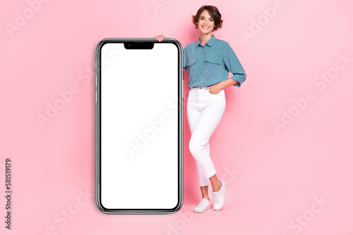 Photo of cute positive lady stylish clothes hand hold big mirror placard banner demonstrate empty space isolated on pink color background