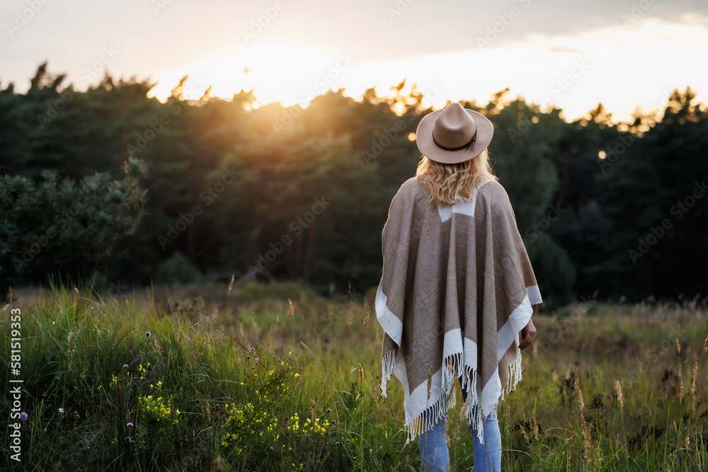 Woman relaxing in nature during sunset for good mental health and her own wellbeing