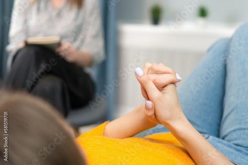 Focus on the hands of a patient lying on the couch at a psychologist's appointment. Woman is being consulted by a psychotherapist. Psychology, psychosomatics, coach