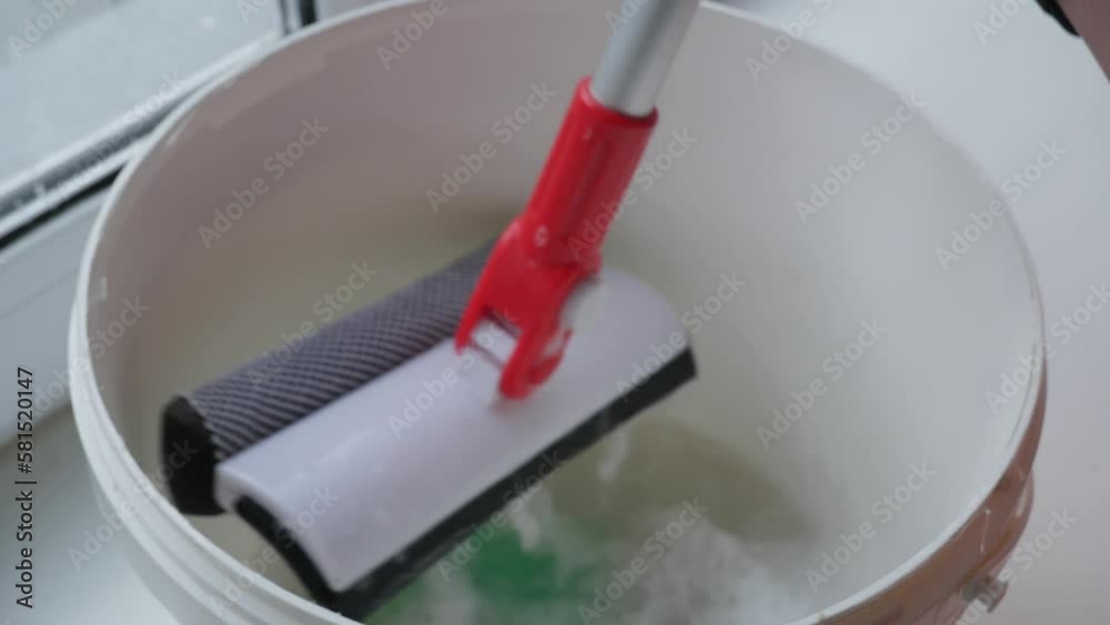 Washing double-glazed windows with a window mop. The girl washes the windows Washing double-glazed windows with a window mop. The girl washes the windows