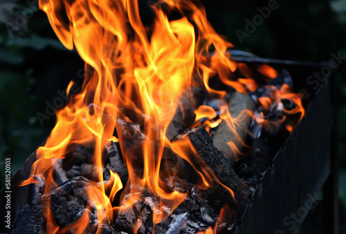 Fire on the grill, grill for cooking fried meat in nature during a picnic or summer vacation. Background Charcoal bonfire for barbeque advertising with restaurant and cafe flames. Menu background