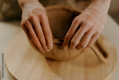 In the pottery workshop the master sculpts clay dishes with his hands on the table