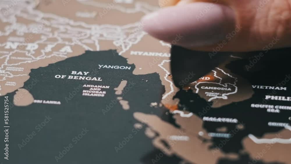 Woman hand erases visited country of Thailand on the travel map