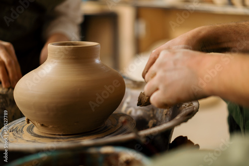 A potter in a pottery workshop removes a jug from the potter s wheel with a potter s knife