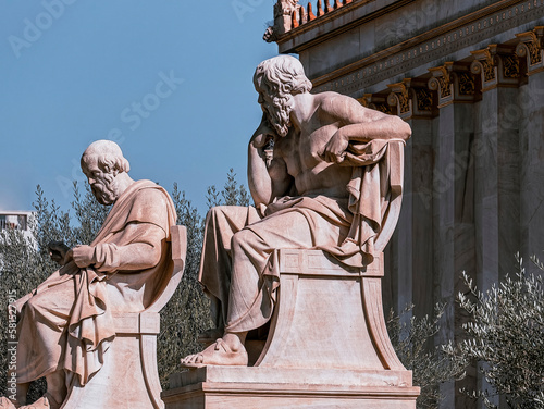 Marble statues of Plato and Socrates, the ancient philosophers, in front of the neoclassical building of the National Academy. Cultural trip to Athens, Greece.