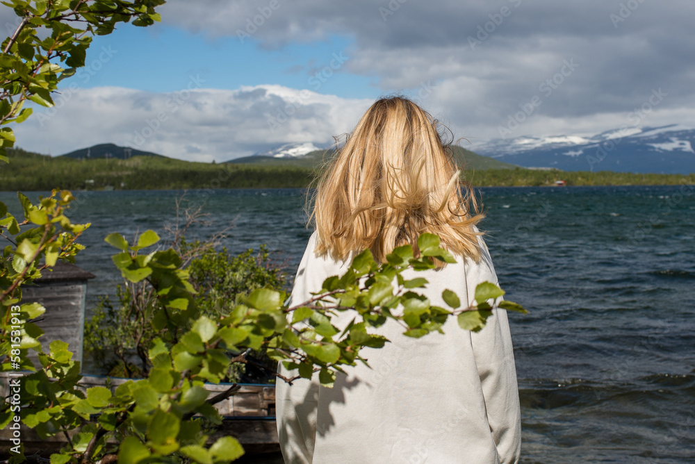 Fototapeta premium Young woman enjoy the beautiful natural scenery in the north. Lake and mountains. Tourist attraction in Norway. Amazing scenic outdoor view. Travel, adventure, relaxed lifestyle. Lofoten Islands