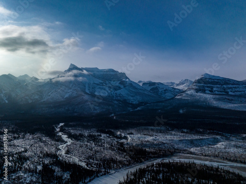 epic aerial view on maountains with river and spruce forest during winter in baff national park  photo