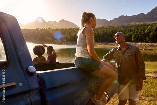Group Of Friends In Pick Up Truck On Road Trip By Lake At Sunset © Monkey Business