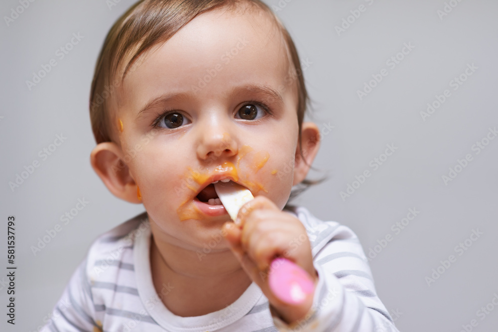 Messy and adorable. a cute little baby girl eating with a spoon. Messy and adorable. a cute little baby girl eating with a spoon.