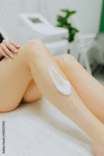 The beauty master is doing a close-up laser hair removal of the legs in a beauty clinic