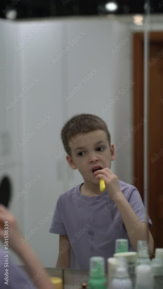 Preteen kid brushing his teeth with a toothbrush in the bathroom.