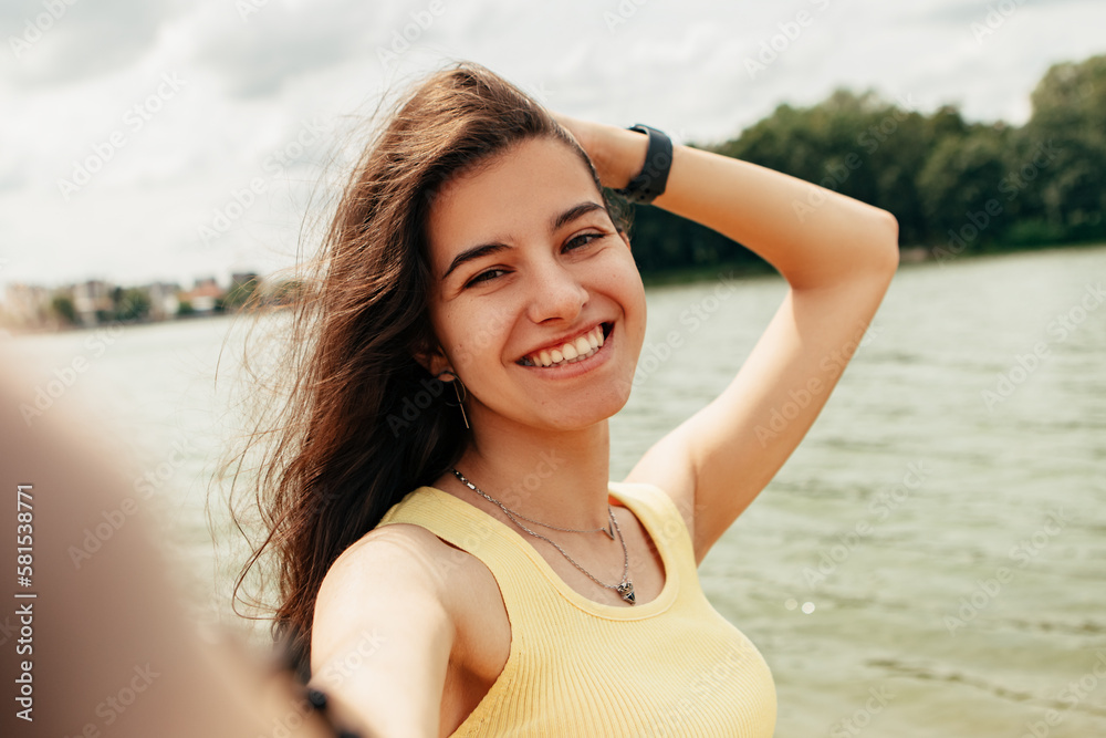 Woman standing smiling laughing near river sea lake, take picture, make selfie hold camera. Female on beach island. Girl tourist on vacation, weekend relaxing resting resort. Lady go shore, sunbathing Woman standing smiling laughing near river sea lake, take picture, make selfie hold camera. Female on beach island. Girl tourist on vacation, weekend relaxing resting resort. Lady go shore, sunbathing