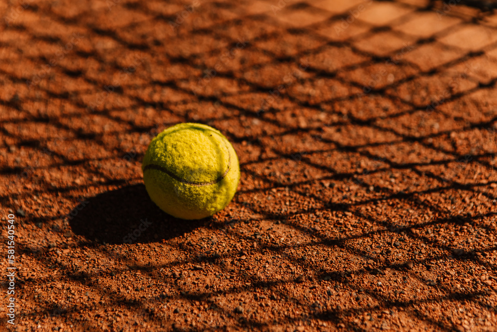 Light orange empty outdoor clay court surface dry grungy ground baseline detail for playing tennis with net shadow in sunny day, yellow green ball, gravel texture background, copy space for text 
 - obrazy, fototapety, plakaty 