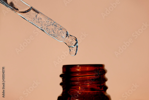 A liquid cosmetic pipette and an amber bottle on a beige background.