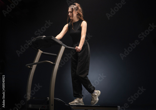 A beautiful athletic girl runs on a treadmill in a fitness club.