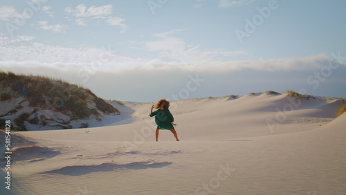 Girl dancing sand dunes at summer evening. Woman performing sensually movements.