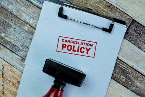 Photography Concept of Red Handle Rubber Stamper and Cancellation Policy text isolated on on Wooden Table