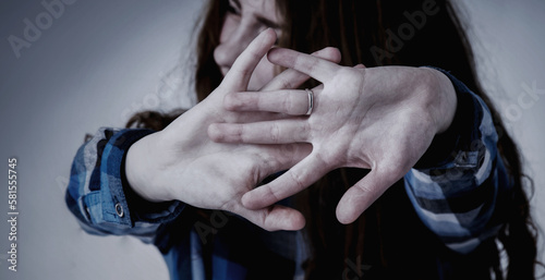 Stop gestute. Portrait of young woman looking in fear with her hand in front of face. Gestures, body language, psychology