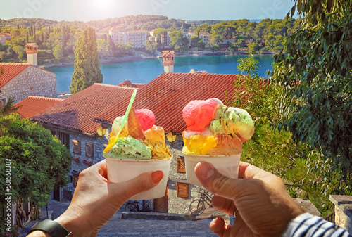 Couple with beautiful bright sweet ice cream of different flavors in the hand.Background of   view of the see and old street  in  Rovinj , Croatia. Traveling concept background