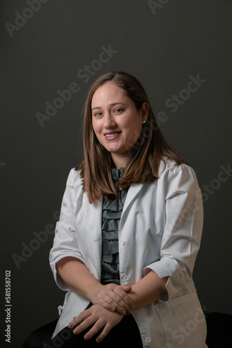 PROFESSIONAL WOMAN: CAUCASIAN LIGHT-EYED MATURE WOMAN, HISPANIC LATINO, PRETTY MOTHER, OVER GRAY BACKGROUND DRESSED IN A DOCTOR'S GOWN AND A STETHOSCOPE, WOMAN DOCTOR, HEALTH AND MEDICINE, HEALTHCARE
