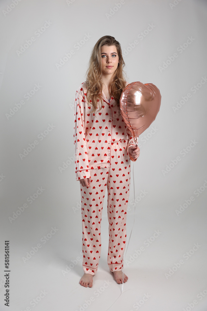girl in heart print pajamas on a white background with heart-shaped gel balls. valentine's day clothes for home and sleep. pajama party girl in heart print pajamas on a white background with heart-shaped gel balls. valentine's day clothes for home and sleep. pajama party