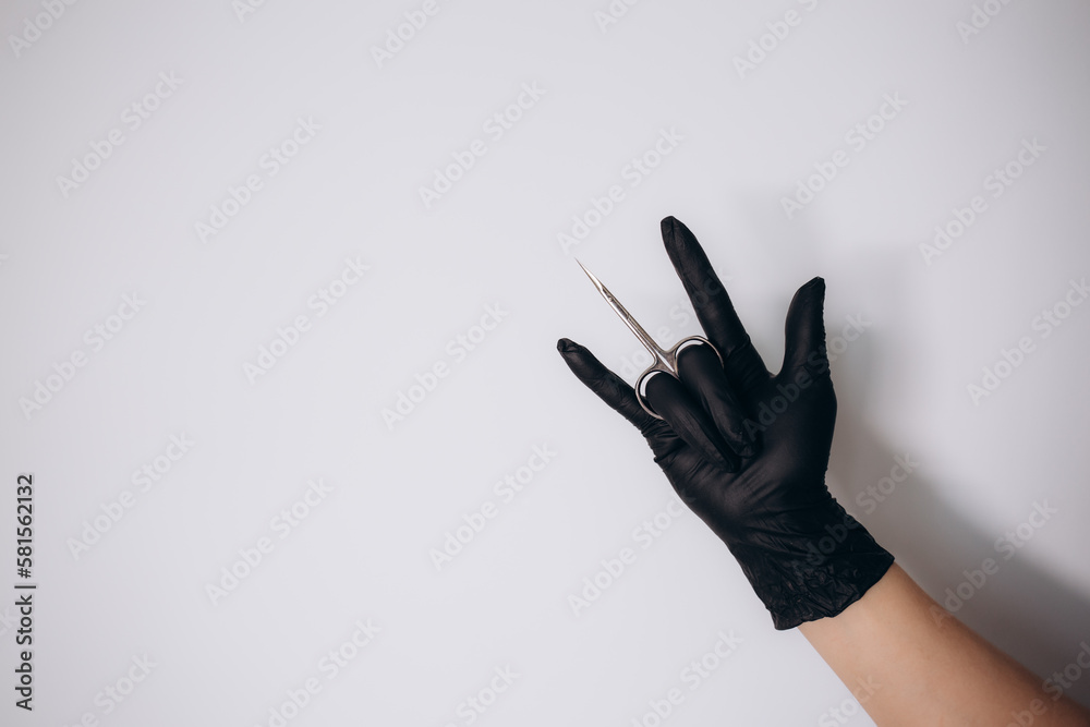 a woman in black gloves holds manicure scissors a woman in black gloves holds manicure scissors