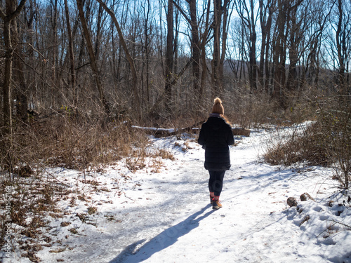 young woman hiking on frozen path on a cold sunny winter day