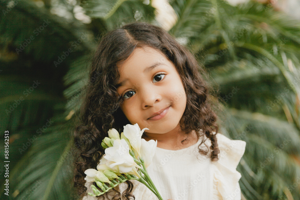 little girl surrounded by tropical leaves. Portrait of a swarthy child with dark hair. Natural cosmetics, health, cleanliness little girl surrounded by tropical leaves. Portrait of a swarthy child with dark hair. Natural cosmetics, health, cleanliness
