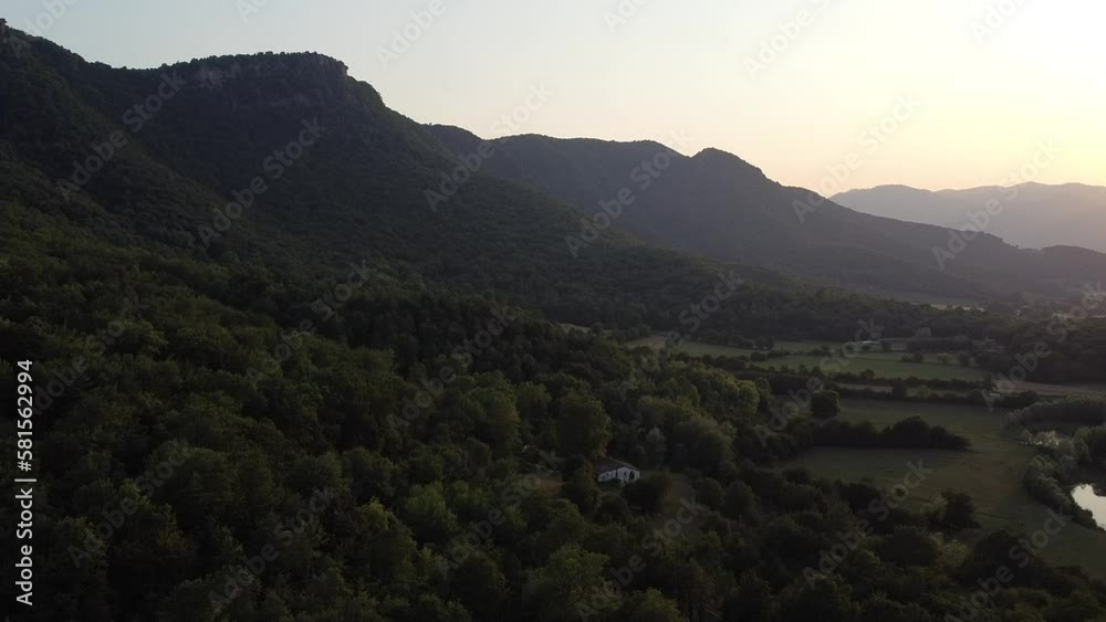 Flying over tree-filled mountains at sunset