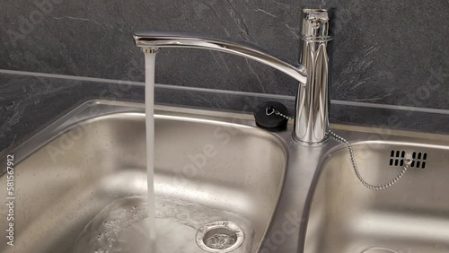 Close up of a kitchen sink with running faucet.