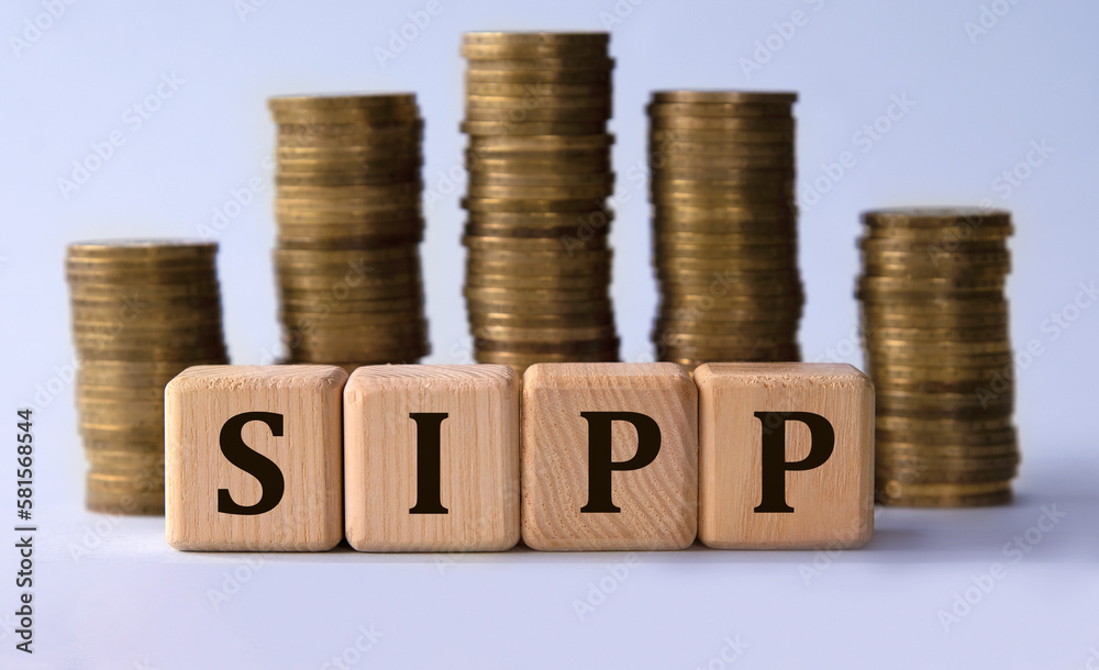 SIPP - acronym on wooden cubes on the background of stacks of coins SIPP - acronym on wooden cubes on the background of stacks of coins